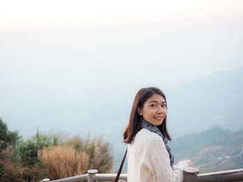 Portrait of young woman in mountains against sky