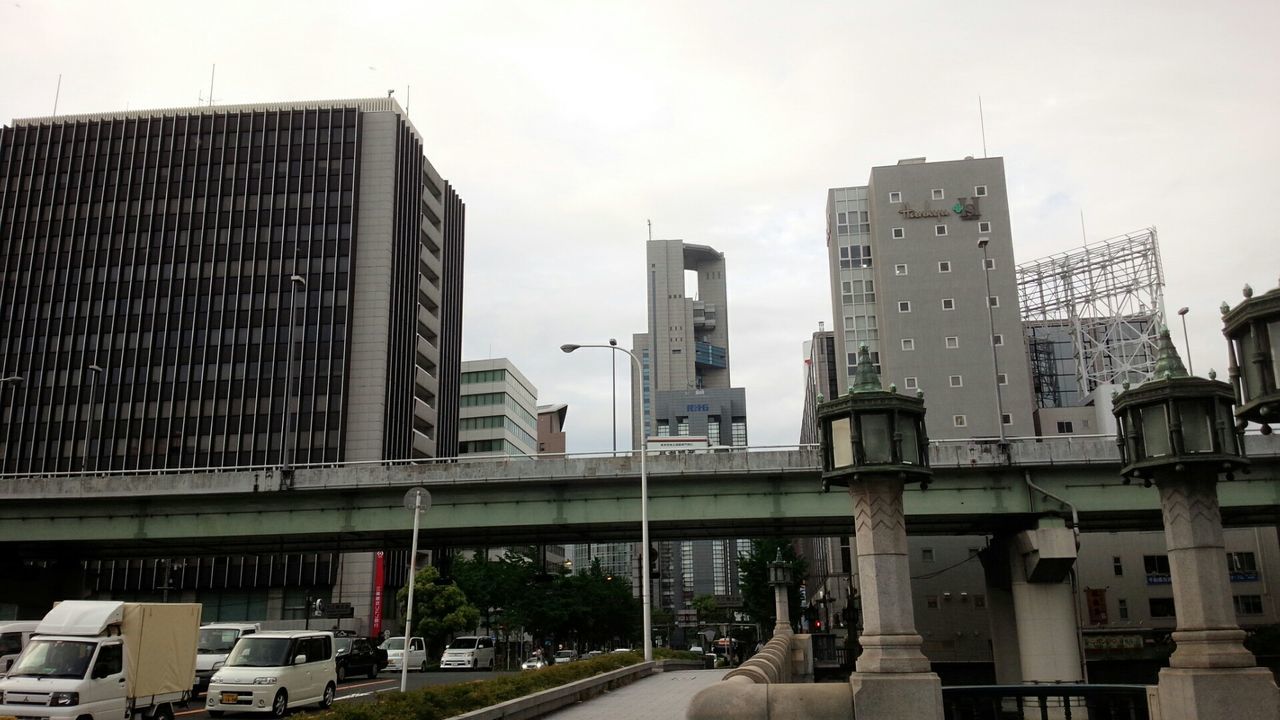 architecture, building exterior, built structure, city, transportation, car, sky, street, building, land vehicle, modern, road, office building, clear sky, day, mode of transport, skyscraper, tower, outdoors, incidental people