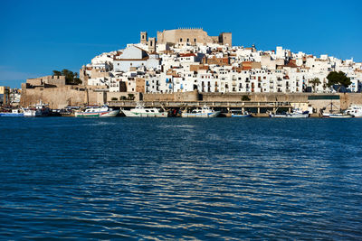 View of town by sea against clear blue sky