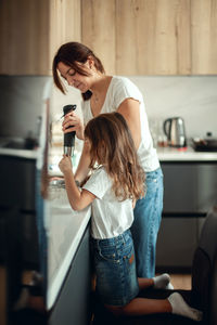 Mother and daughter preparing food while standing in kitchen at home