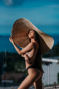 Portrait of young woman standing against sky