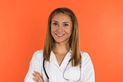 Portrait of young woman standing against yellow background