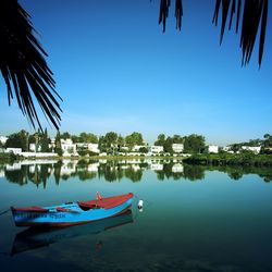 Boats moored in lake against clear blue sky