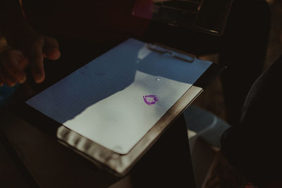 Cropped hand of person by clipboard on table