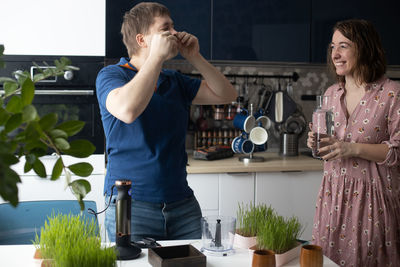 Side view of couple holding hands while standing at home