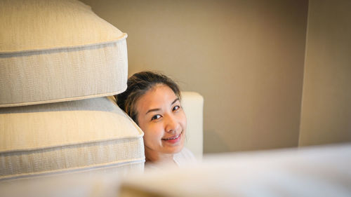 Portrait of young woman sitting on bed at home