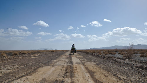 Rear view of man riding motorcycle on road