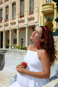 Young woman looking away while standing against building
