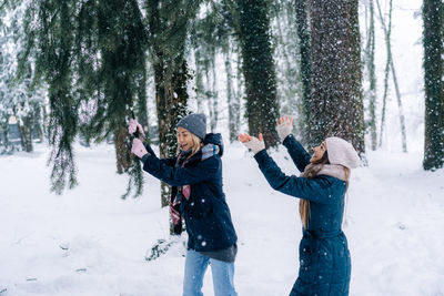 Young women are walking and fooling around in the park on a snowy winter day.