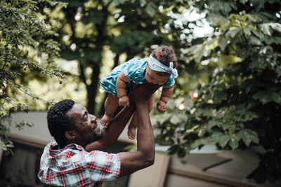 Father carrying daughter on shoulder outdoors