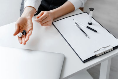 Midsection of woman holding paper with text on table