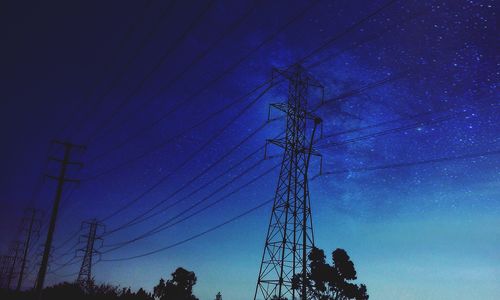 Low angle view of electricity pylon against blue sky