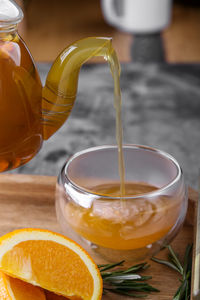 Cropped image of teapot pouring drink in drinking glass