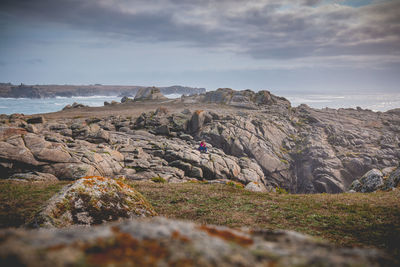 Woman sitting on rock against sea