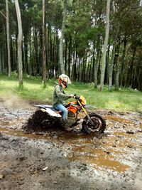 Man riding motorcycle on mud in forest