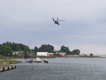 Airplane flying over river against sky