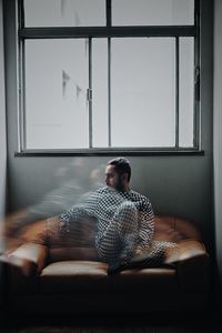 Rear view of woman sitting on bed at home