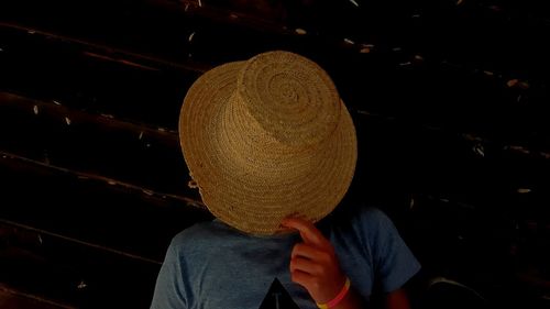 Rear view of man holding hat at night