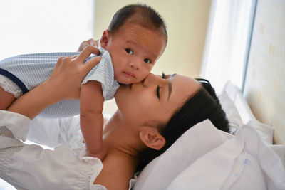 High angle view of mother kissing daughter on cheek while sitting at home