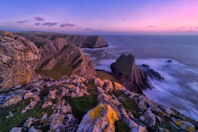 Rock formations in sea against sky during sunset