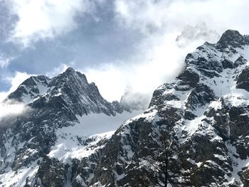 Low angle view of snowcapped mountains against sky