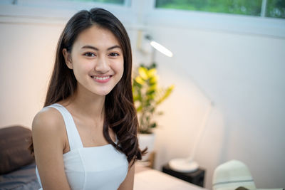 Portrait of young woman looking away against wall