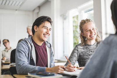 Smiling young man with female friend in classroom