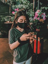 Beautiful young woman standing by flowering plant