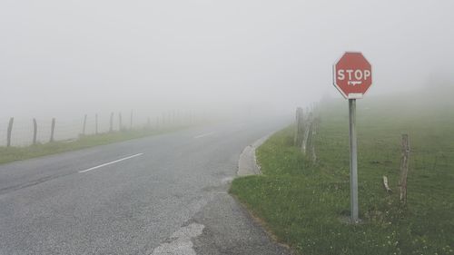 Road sign against sky during foggy weather
