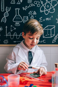 Boy wearing lap coat while sitting in classroom