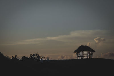 Silhouette lifeguard hut on beach against sky