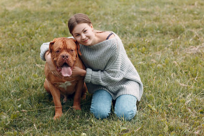 Portrait of teenage girl with dog on grass