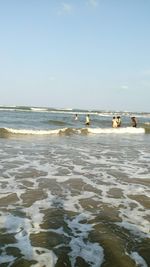 Group of people on beach against clear sky