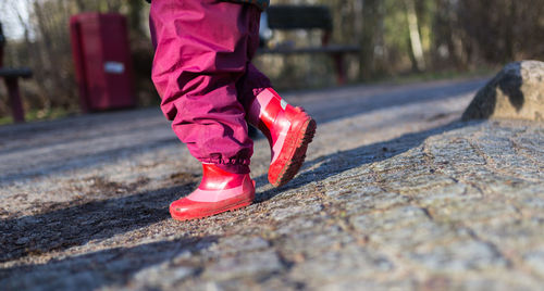 Low section of girl wearing red shoes walking on street