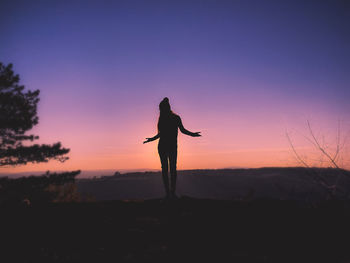 Silhouette man standing on field against sky during sunset