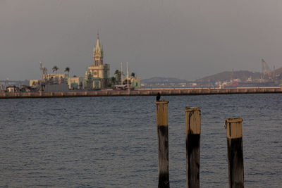 Wooden posts in sea with buildings in background
