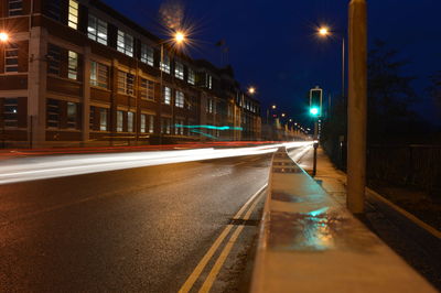 Light trails on road against sky in city at night