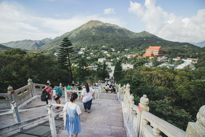 Group of people by buildings against mountain range