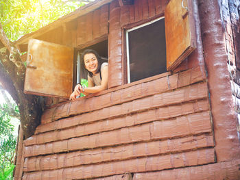 Portrait of smiling young woman looking through window