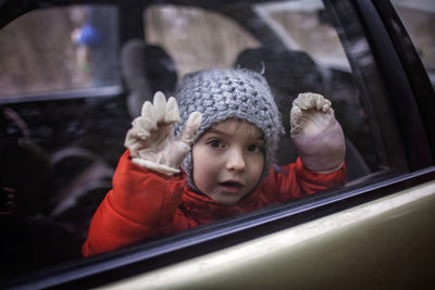 Little boy wearing respirator mask and medical gloves looking through a car window, stay safe