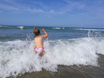 Rear view of boy on beach against sky