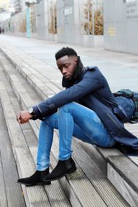 Young man sitting on bench in city