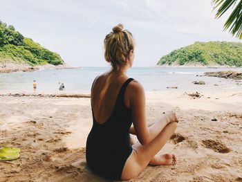 Rear view of woman exercising on beach