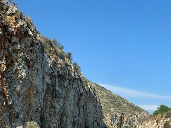 Low angle view of rock formation against clear blue sky