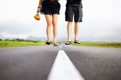 Low section of couple jumping on road