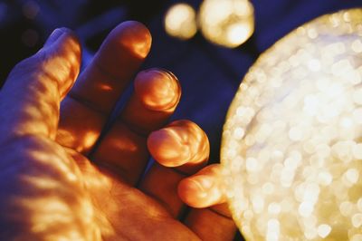 Close-up of human hand by illuminated lantern