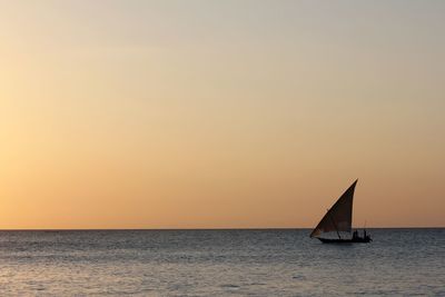 Sailboat sailing on sea against sky during sunset