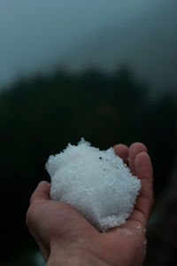 Close-up of hand holding ice cream against sky