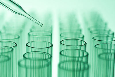 Close-up of pipette over test tubes against green background