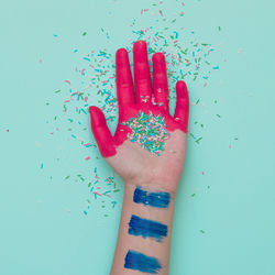 Close-up of human hand against colored background